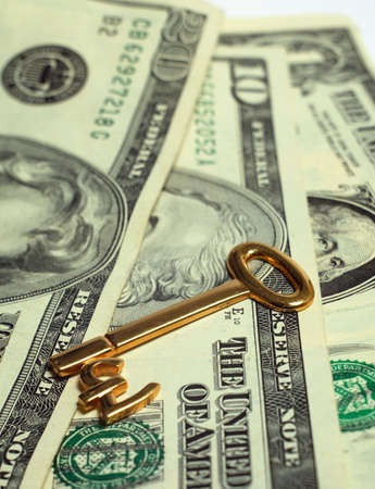 A gold key with the pound symbol lying on top of US currency notes, symbolising currency exchange, unlocking opportunities, locking in profits, etc.の写真素材