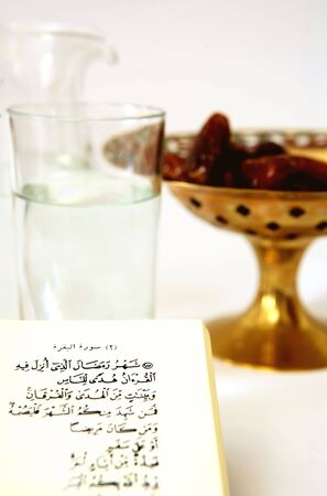 The holy Qur'an verse about Ramadan with a bowl of dates and a jug and glass of waterの写真素材