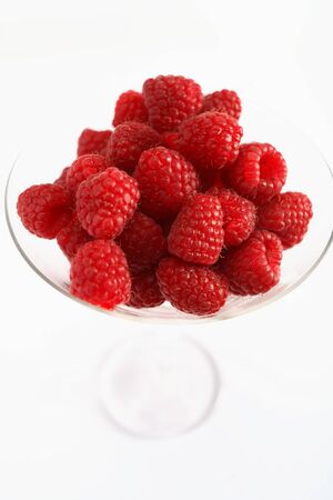 A cocktail glass full of raspberries