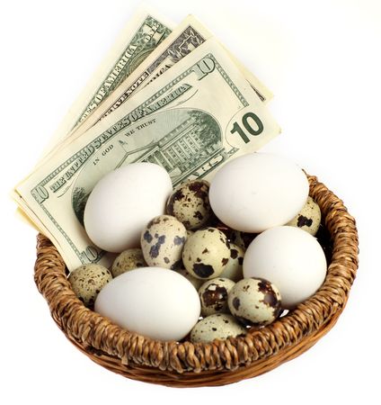 A basket containing money and all kinds of different eggs - hens, quails and artificial - over a white background. Financial or business concept for saving, investment or financial managementの写真素材