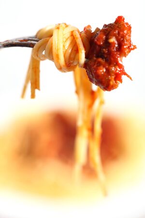 An Italian-style meal of spaghetti and meatballs in tomato sauce, focus on a single meatball on a fork with pastaの写真素材