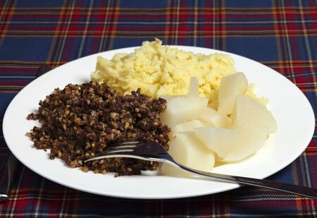 A Burns Night supper of haggis, tatties and neeps on a tartan backgroundの写真素材