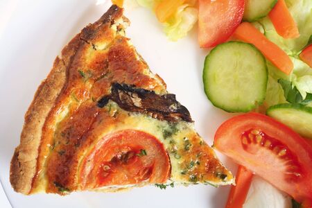 Slice of mushroom quiche on a plate with a salad