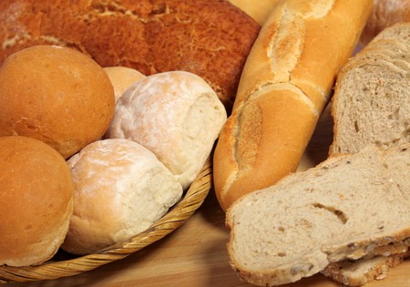A breadboard and basket full of bread.