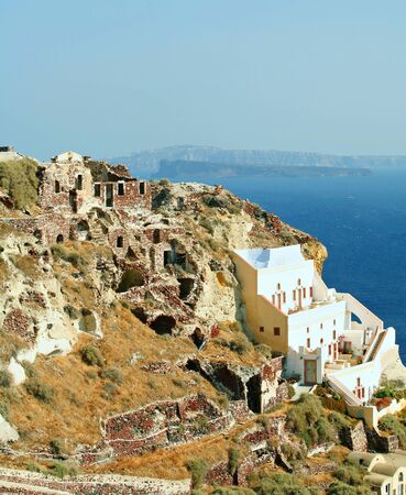 Part of the picturesque Santorini village of Oia, where the blue-domed churches are a major attraction. The ruins left from when the village was destroyed in an earthquake in 1953 blend in so well they go almost unnoticed.の写真素材