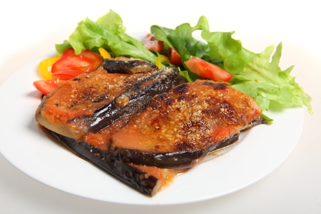 A meal of eggplant parmigiana (eggplant baked with tomato passata and parmisan) with a salad of lettuce, rocket, capsicum and tomatoの写真素材