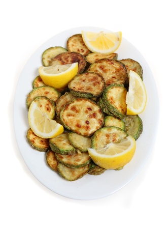 A plate of fried courgette or zuccini rings on a plate with lemon wedges, viewed from above.の写真素材