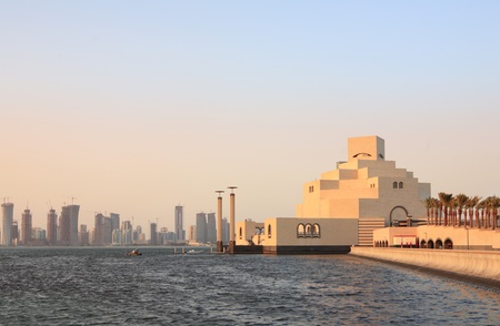 The Museum of Islamic Art in Doha, Qatar, at sunset with the emerging high-rise skyline behind it,...