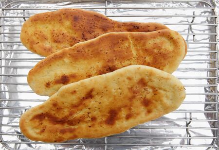 Homemade Indian naan bread cooling on a rack