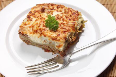 A slice of homemade lasagne verdi on a plate with a fork, high angle viewの写真素材