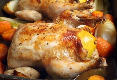 Chickens roasting on a bed of carrot, onion, garlic and celery, and stuffed with a lemon and some herbs  Using a bed of fresh vegetables is a fashionable way of preparing roasts, after being recommended by a number of celebrity TV chefs の写真素材