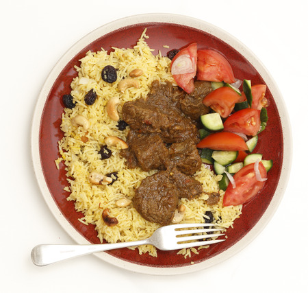 High-angle view of a homemade beef madras curry served with saffron, raisin and roast cashew nut pilau rice and a salad of tomato, cucumber and shallots.の写真素材