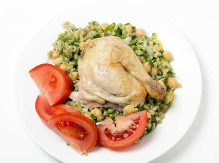Freekeh salad with chickpeas, onion, parsley, celery, and a lemon juice and olive oil dressing, and a chicken leg with tomatoの写真素材