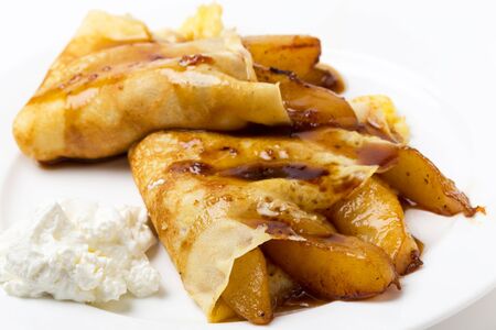 English-style pancakes filled with caramelised pears, topped with light caramel sauce and served with yoghurt.の写真素材