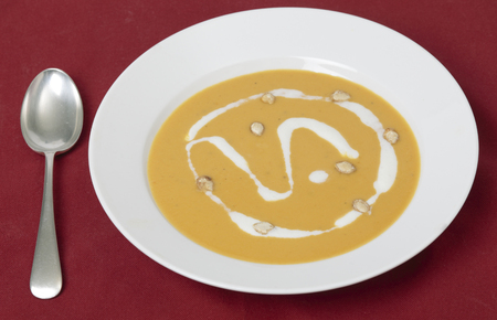 Traditional French butternut squash cream soup with soured cream and toaste squash seed garnish.の写真素材