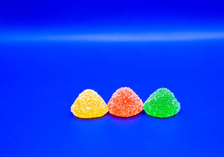 Sugar gummy candies and gelatin candy on a blue backgroundの写真素材