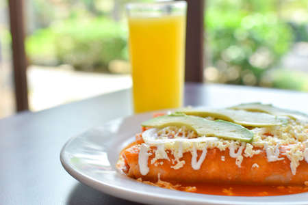 Breakfast of red tomato enchiladas with chicken and beef cream with cheese and avocado accompanied...