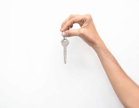Hand holding a metal house keys on an isolated white backgroundの写真素材