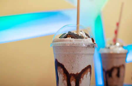 Shaved ice drinks with coffee and chocolate chip cookie in interior with neon wallの写真素材