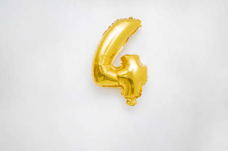 a number four celebration metallic gold colored helium balloon on an isolated white backgroundの写真素材
