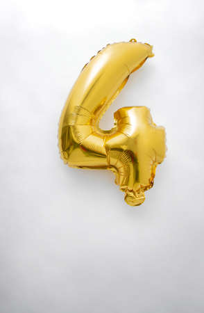 Vertical photograph of a number four celebration metallic gold colored helium balloon on an isolated white backgroundの写真素材
