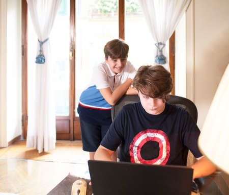 teen boys school students watching online webinar learn on laptop sit in desk distance e-learning on...