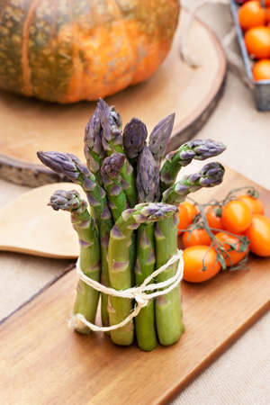 Isolated Fresh green asparagus on old wooden tablewith tomatoes and a pumpkinの写真素材