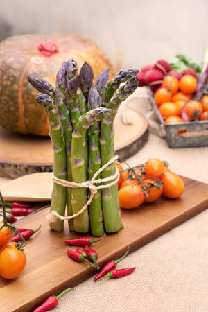 Isolated Fresh green asparagus on old wooden tablewith tomatoes and a pumpkinの写真素材