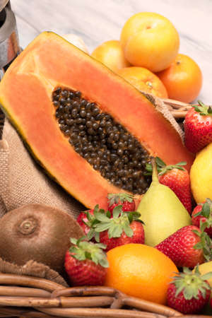 Basket of tropical fruits, oranges, pears kiwi papaya with a mixer on a wooden table. Verticalの写真素材