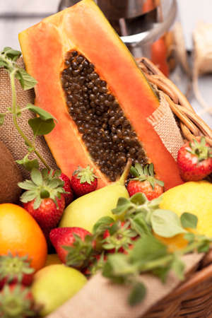 Basket of tropical fruits, oranges, pears kiwi papaya with a mixer on a wooden table. Verticalの写真素材