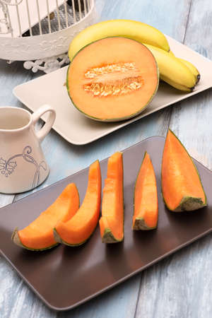 Fresh and various fruits isolated in a shabby chic background. melon and bananas. Vertical view from the topの写真素材