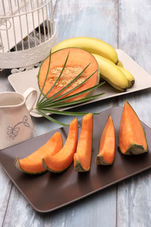 Fresh and various fruits isolated in a shabby chic background. melon and bananas. Vertical view from the topの写真素材