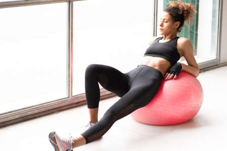 Young and beautiful woman having relax after workout in a gym isolated White background horizontalの写真素材