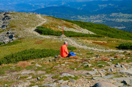 Hiker sitting on the top of a mountain and enjoying the viewの写真素材