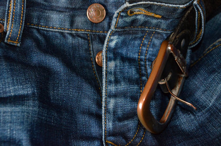 Jeans with belt buckle closeup. Blue denim jeans background.