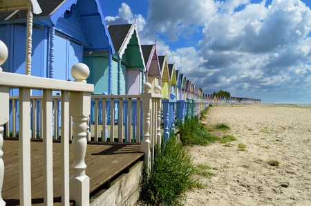 A line of brightly colored beach huts by the oceanの写真素材