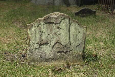 Half buried ancient weathered and flaking gravestoneの写真素材