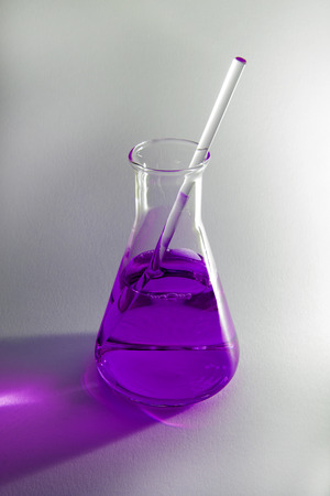 Science flask containing a purple chemical on a plain backgroundの写真素材