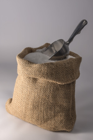 Small open sack of sugar with a metal scoopの写真素材
