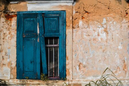 broken blue window with orange wall of old buildingの写真素材