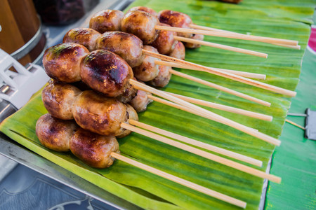 thai sausage with stick sale on banana leaf at the street marketの写真素材