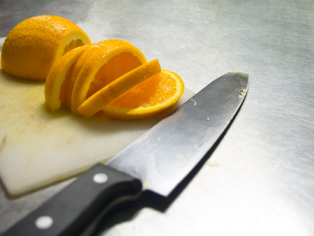 sliced orange with knife in kitchen.の写真素材