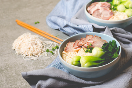 delicious egg noodle with red pork and vegetable in bowl decoration with chopstick on table,thaifood,selective focus.の写真素材