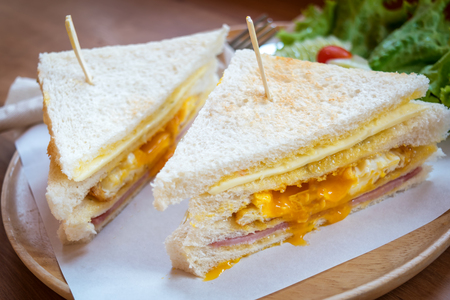 slice ham cheese egg sandwich breakfast with fresh vegetable cucumber on wooden table ,selective focus の写真素材