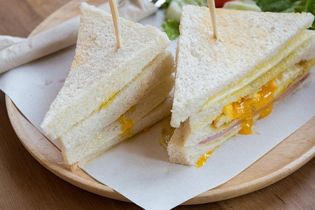 slice ham cheese egg sandwich breakfast with fresh vegetable cucumber on wooden table ,selective focus の写真素材