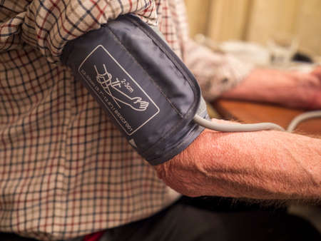 Older man checking blood pressure at home
