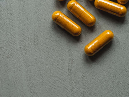 yellow turmeric capsules on a grey wooden background copy spaceの写真素材