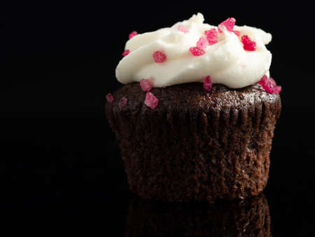 chocolate cupcake with white frosting on a black backgroundの写真素材