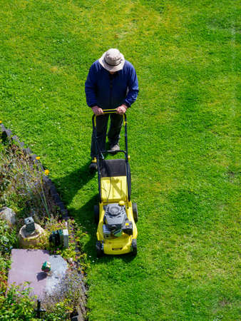 ariel view man cutting the grass with a mower in his gardenのeditorial素材
