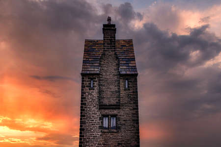 Rivington pigeon tower look out on winter hill West pennine moors tall thin fairy tail like structure against a dramatic sky building depicts a human faceのeditorial素材
